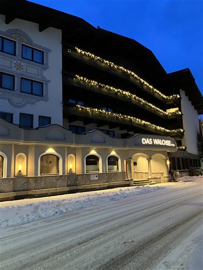 A beautiful hotel with festive lighting. The surroundings are covered in snow and it is twilight.