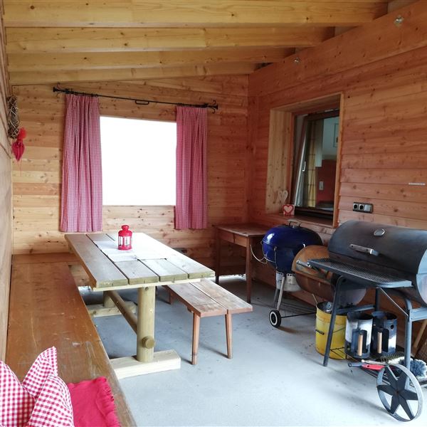 Ein gemütlicher überdachter Terrassenbereich mit einem großen Tisch und Stühlen. 2 Lampen und eine Wärmelampe wurden inzwischen auch installiert, so kann man bei jedem Wetter und auch von Frühling bis Herbst draußen sitzen.