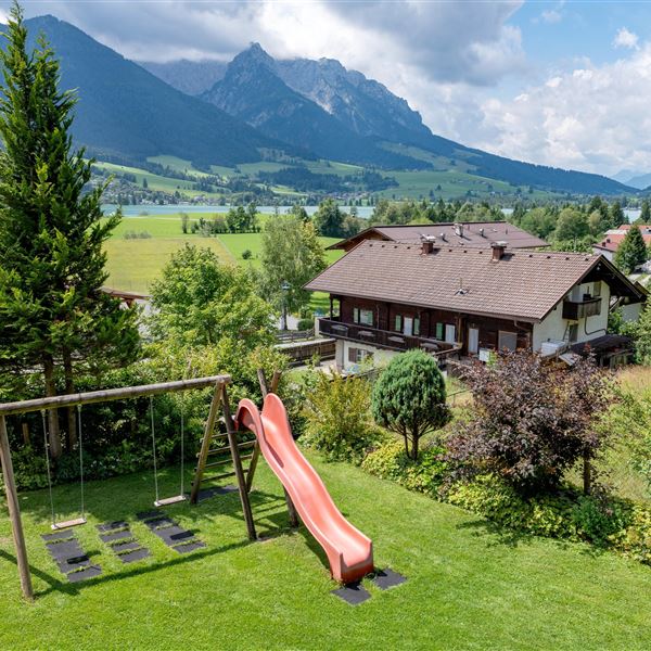 Ein schöner Garten mit einer Rutsche und einer Schaukel.